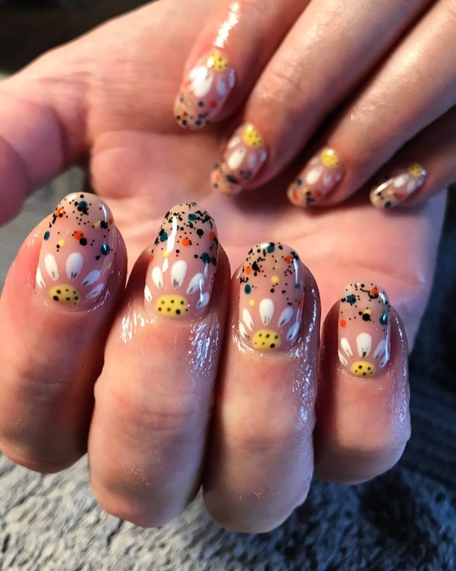 Foto com destaque nas unhas com nail art de bolinha, dessa vez formando uma flor amarela e branca e desenhos de bolinhas ponta.