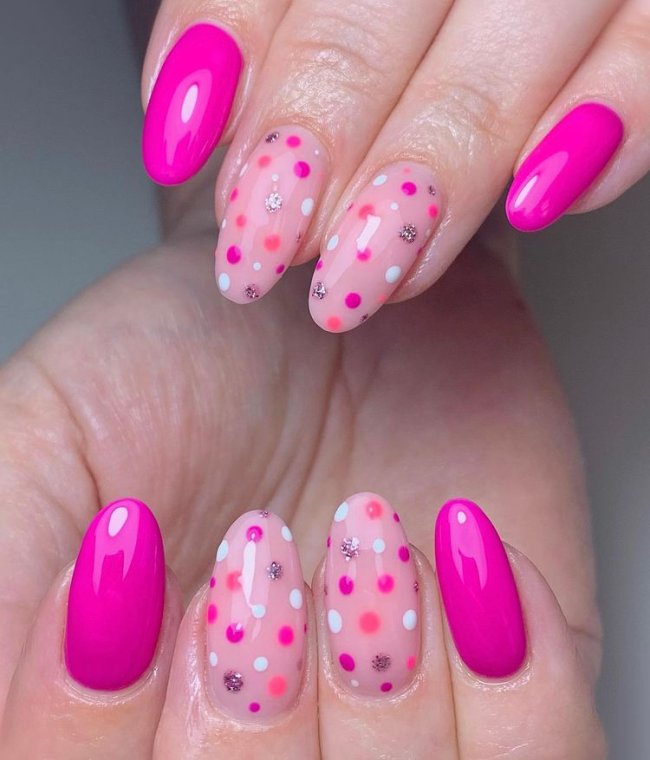 Foto com destaque nas unhas com nail art de bolinha, dessa vez com fundo rosa e bolinhas em tom de rosa, salmão, lilás e azul.