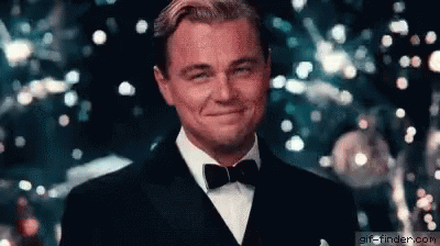 Leonardo DiCaprio erguendo uma taça com drink em sinal de agradecimento, tipo brindando algo