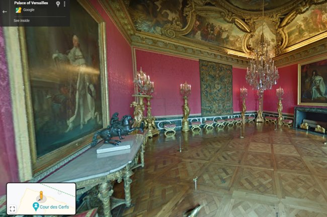 Imagem do Palácio de Versalhes, na França. O cômodo é rosa com detalhes dourados, e tem muitos lustres e quadros da realeza