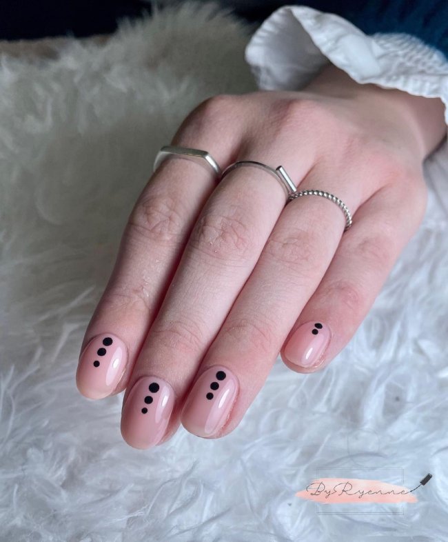 Foto com destaque nas unhas com nail art de bolinha, dessa vez com fundo transparente e três bolinhas pretas no centro da unha.