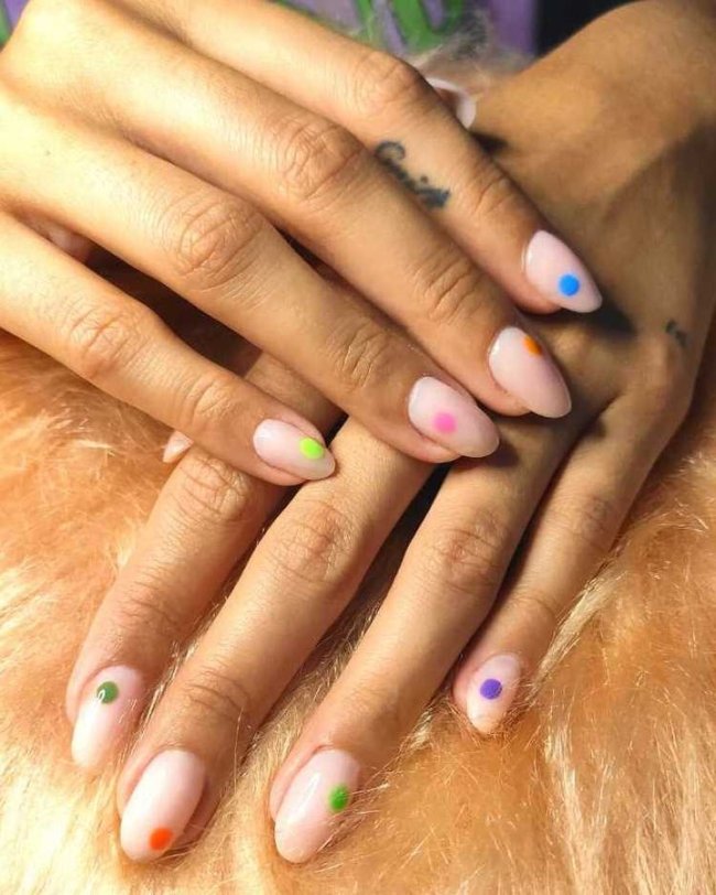 Foto com destaque nas unhas com nail art de bolinha, dessa vez com várias cores, entre elas, azul, verde, rosa, laranja e roxo.