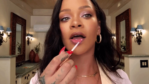 Gif da Rihanna passando gloss nos lábios e fazendo uma cara de surpresa.