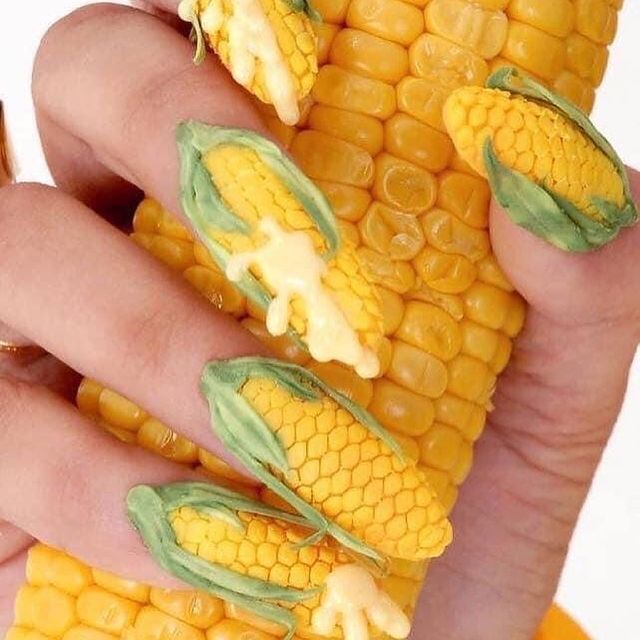 Foto com destaque nas unhas que estão com nail art inspirada em milho