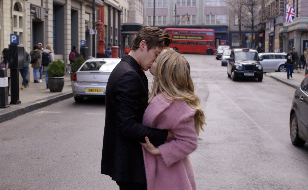 Hardin e Tessa se beijando na rua em cena de After - Depois do Desencontro; ele usa um casaco preto enquanto ela usa um rosa claro com pelinhos