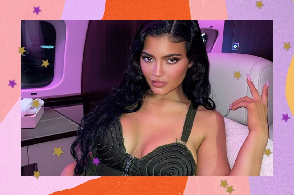 Kylie Jenner em um jatinho particular com uma mão levantada