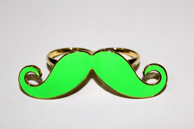 Foto de um anel verde neon com formato de bigode.