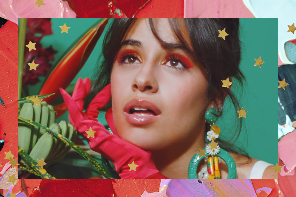 Camila Cabello com luva e sombra vermelha no clipe de Don't Go Yet; ela está com expressão pensativa olhando para cima com elementos verdes ao fundo; a margem é uma textura de tintas em tons de vermelho, verde, roxo e rosa com estrelas amarelas como decoração