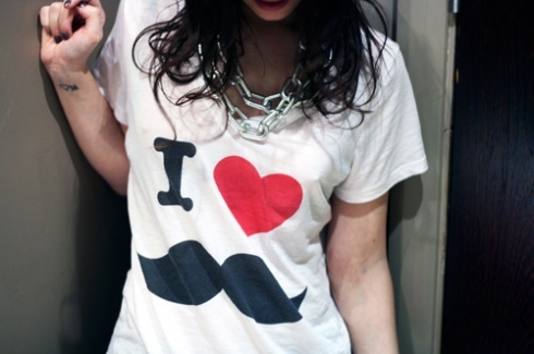 Foto da camiseta branca com estampa de bigode em uma mulher.