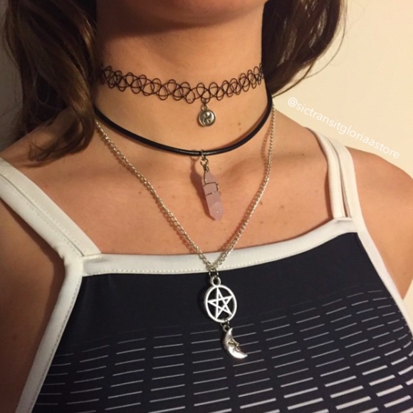 Foto de colares em uma mulher. Ela usa uma gargantilha que imita uma tatuagem, uma com um pingente de pedra e um colar com pingente de estrela.