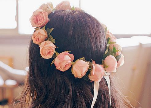 Foto do cabelo de uma menina com uma coroa de flores rosa.