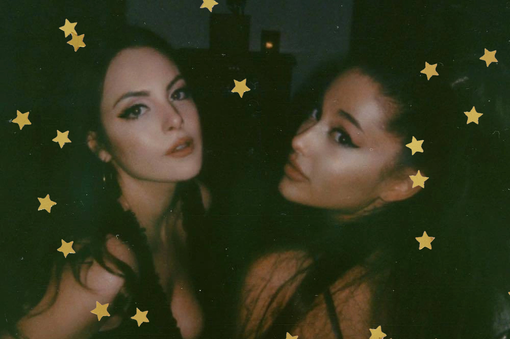 Elizabeth Gillies e Ariana Grande posando para foto; Ariana está de costas olhando para câmera por cima do ombro enquanto Liz está inclinada para perto da amiga; as duas estão com expressões sérias; estrelas amarelas decoram a imagem