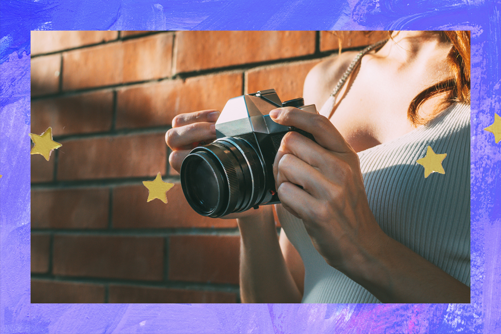 Imagem de uma garota ruiva segurando uma máquina fotográfica nas mãos