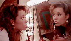 Gif de uma cena do filme Teen Witch com as personagens se maquiando em frente ao espelho.