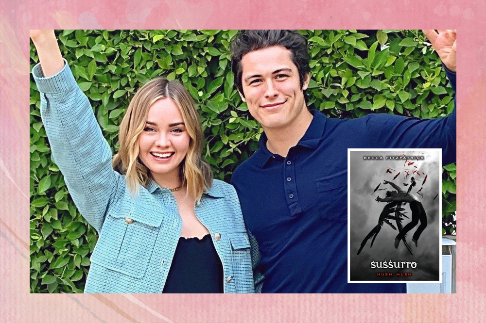 Liana Liberato e Wolfgang Novogratz posando para foto; Liana e Wolf estão com os braços levantados sorrindo para câmea; a capa do livro aparece ao lado em tons de preto com um anjo caindo e o título "Sussurro"; a margem é uma textura em tons de rosa