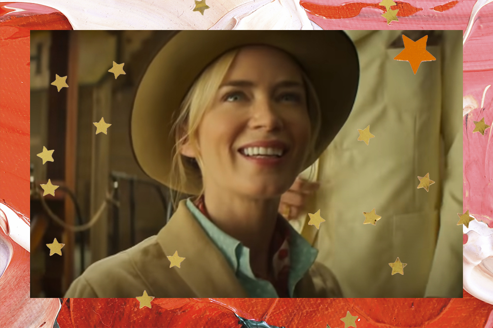 Emily Blunt com camisa azul, chapéu e casaco bege sorrindo em cena de Jungle Cruise; ela está com um olhar sonhador e de admiração para cima; a margem é uma textura de tintas em tons de vermelho, rosa e branco com estrelas amarelas e laranjas como decoração