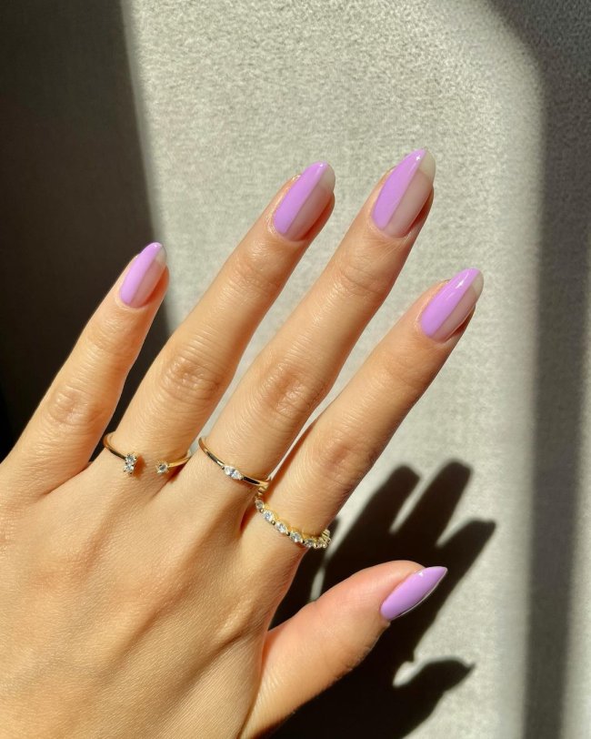 Foto com close nas unhas e tem nail art com traços na cor lilás.