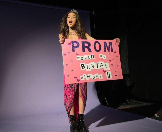 Olivia Rodrigo em imagem de divulgação do show virtual Sour Prom. Ela usa vestido rosa, com tiara de princesa e segura cartaz rosa.