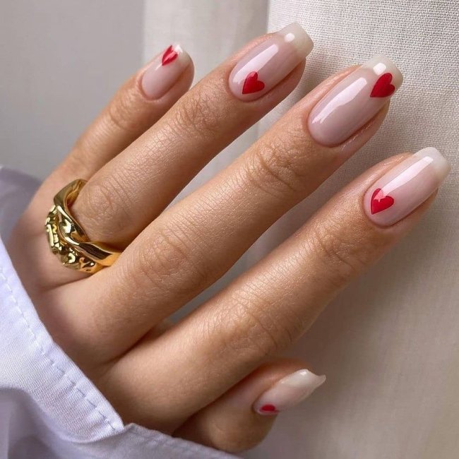 Foto com foco nas mãos exibindo a nail art das unhas. No caso, corações vermelhos.
