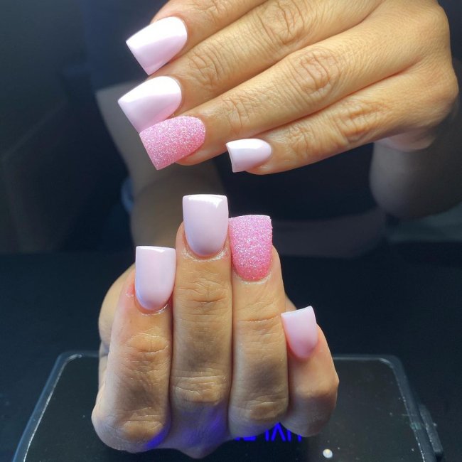 Foto com foco nas unhas com formato duck feet. As unhas estão esticadas. Com degrade rosa e branco.