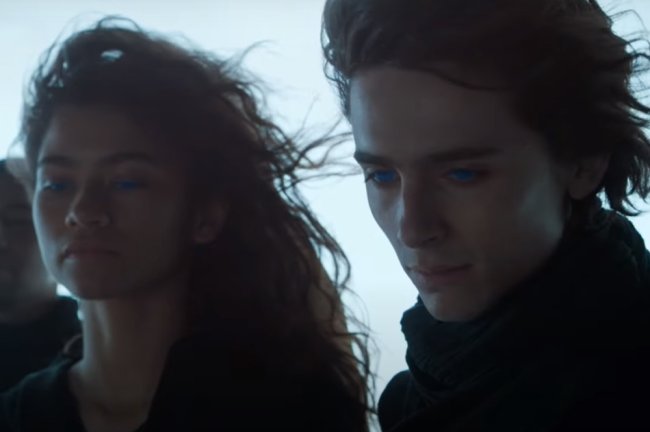 Zendaya e Timothée Chalamet em cena de Duna; os dois estão com olhos azuis brilhantes e com o vento batendo nos cabelos; eles tem expressões sérias