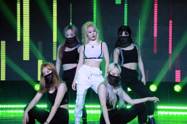 3YE_divulgação2 Integrantes do 3YE em show virtual, a integrante do centro está vestida com roupa toda branca enquanto as demais estão ao seu redor com roupas pretas e máscara também preta