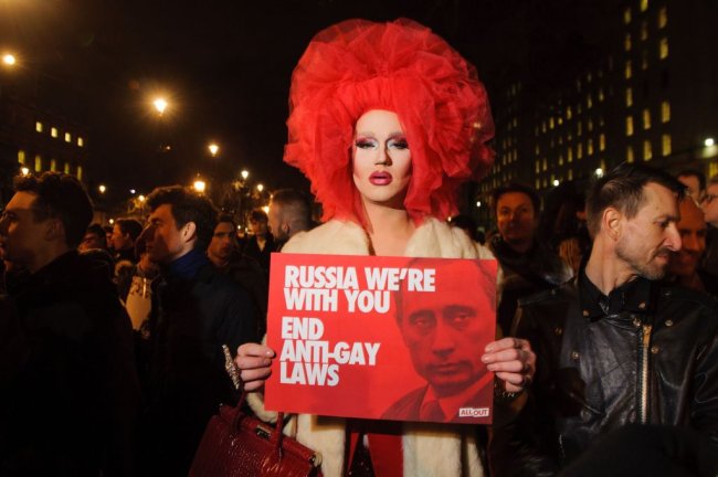 Ser lésbica garantiu a essas mulheres prisão, exílio e o pior do mundo Drag protesta contra as leis anti_gays russa, segurando uma plava vermelha com a foto de Putin. Ela usa uma peruca vermelha e um casaco bege