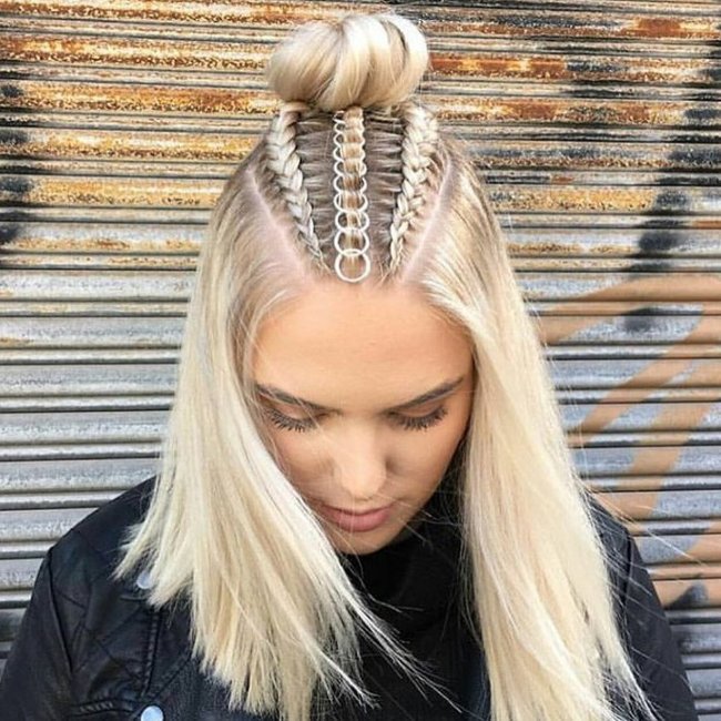 cabelo com piercing Jovem olhando para baixo com coque no topo da cabeça, trancinhas e piercings.