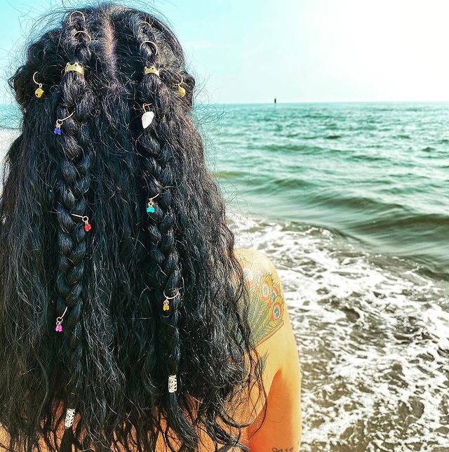 cabelo solto com trancinha Jovem de costas posando com tranças com piercings por toda extensão.