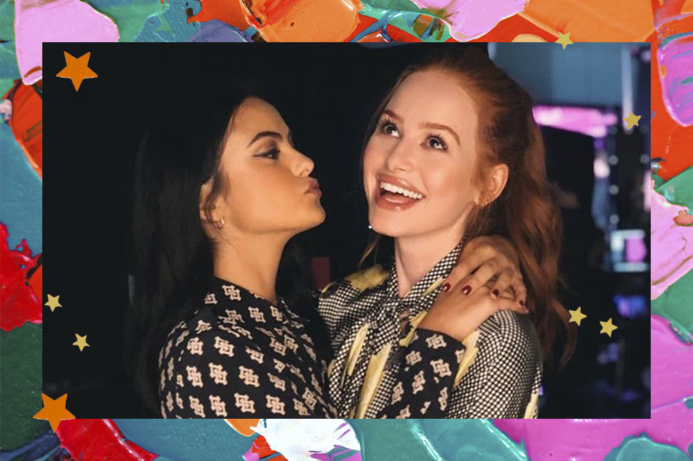 Montagem em fundo colorido de Camila Mendes e Madelaine Petsch. Camila está de lado, fazendo biquinho e abraçando amiga, enquanto Madelaine está sorrindo e olhando para cima.