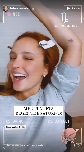 Larissa Manoela sorrindo e de braço levantado, mostrando a tatuagem de Saturno próxima ao seu cotovelo