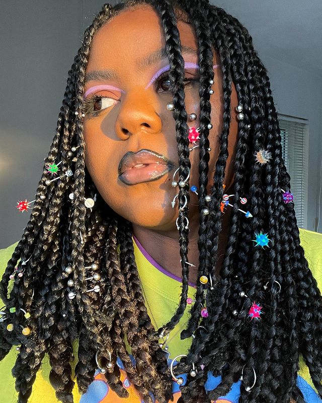 trancinhas com piercing Jovem com expressão séria e olhando para lateral, posando com trancinhas por todo o cabelo.