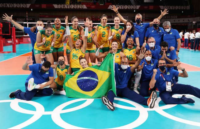 vezes que a o vôlei do Brasil provou que união feminina faz toda diferença Jogadores e equipe técnica do Brasil posa para foto após vaga garantida na semifinal. Eles estão felizes, com os braços para a cima e segurando a bandeira do Brasil