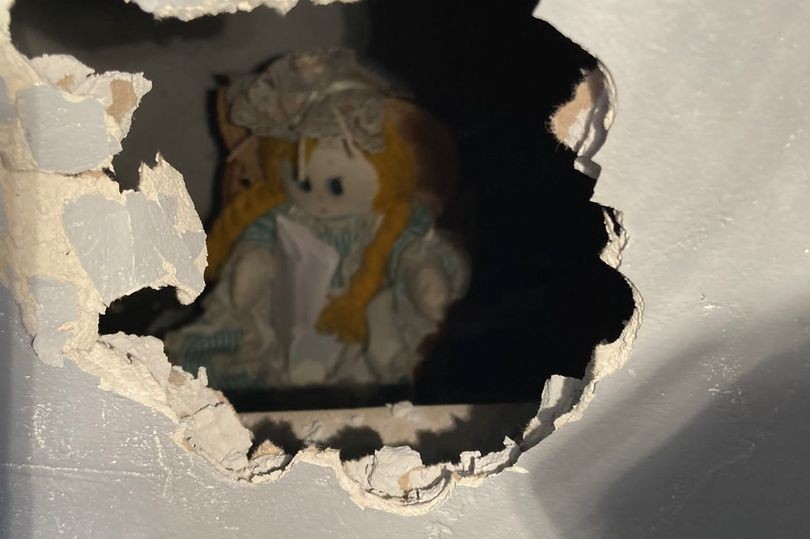 Foto de uma boneca ruiva encontrada escondida na parede de uma casa junto de um bilhete dizendo que ela havia matado os familiares daquela casa nos anos 60
