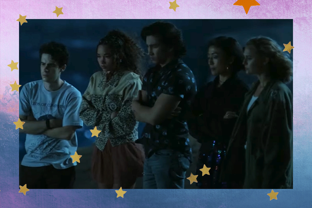 Cinco personagens adolesentes do filme com os braços cruzados em volta do corpo indicando frio; eles estão com expressões sérias e assustadas olhando para frente em um ambiente aberto durante a noite