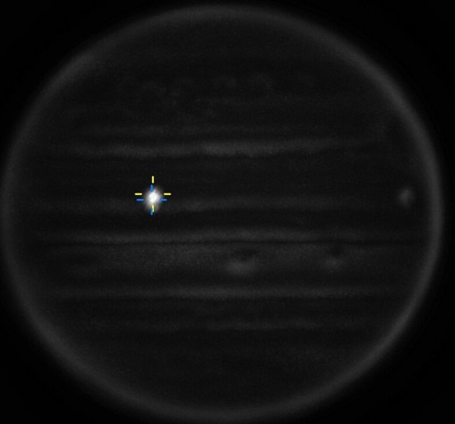 Imagem de telescópio da superfície de Júpiter. Tem um clarão na lateral esquerda superior, que sinaliza a colisão de um asteroide