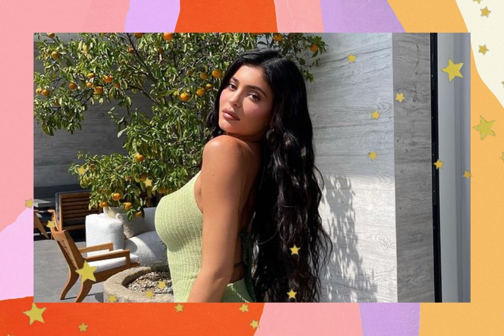 Montagem com o fundo colorido e detalhe de estrelas douradas com a foto da Kylie Jenner. Ela usa um vestido verde, cabelo longo solto e maquiagem com tons básicos. Ela está de perfil, olha para a câmera e não sorri.