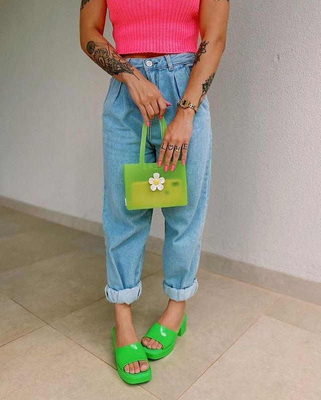 Foto do look de uma mulher. Ela usa uma blusa rosa, calça mom jeans, bolsa verde e tamanco verde. A foto não mostra o rosto dela.