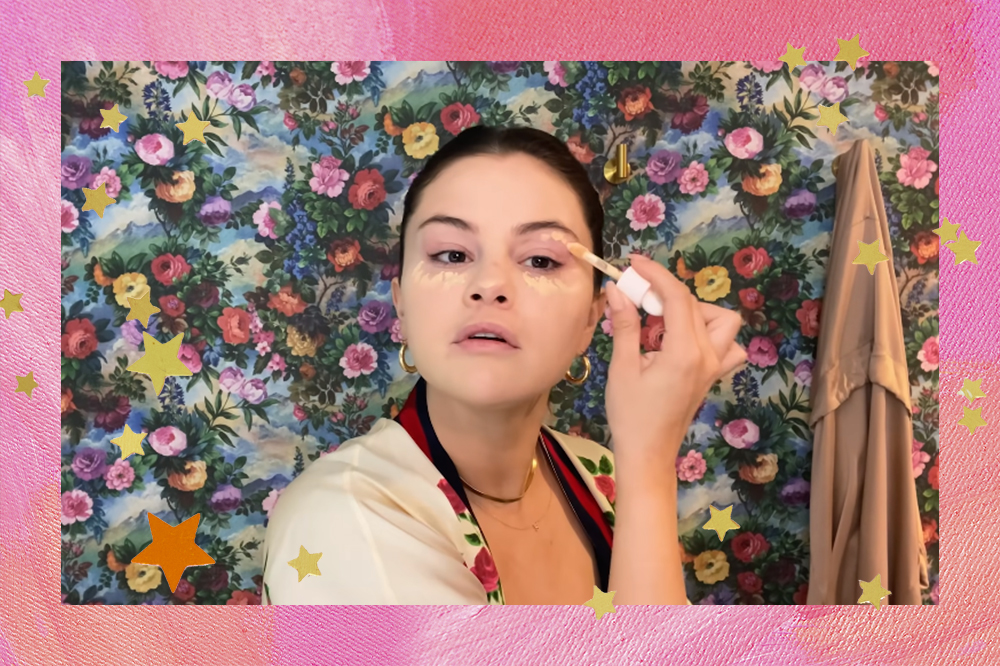 Montagem com foto da Selena Gomez passando corretivo nos olhos em fundo rosa e estrelinhas douradas e laranjas