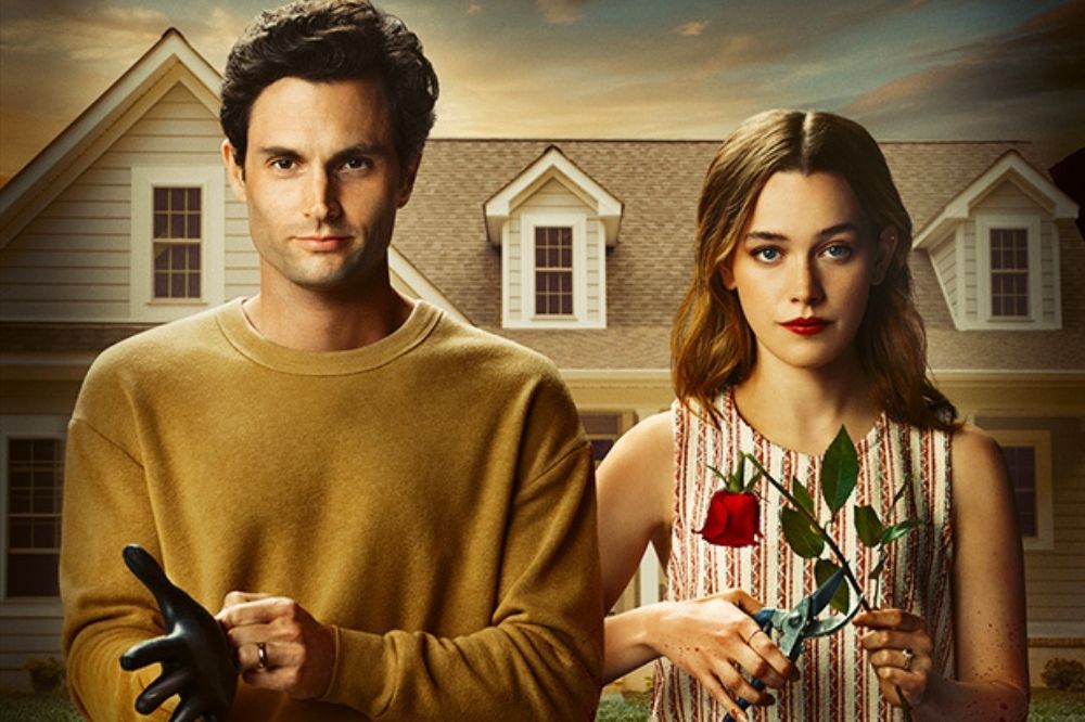 Foto promocional da série You da Netflix; Joe está colocando uma luva preta sorrindo levemente e Love cortando uma rosa vermelha em frente a uma casa