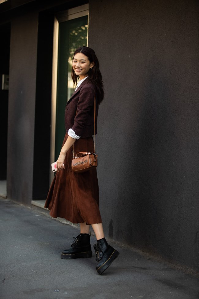 Jung Ho-yeon posando em frente a parede preta usando saia e coturno.