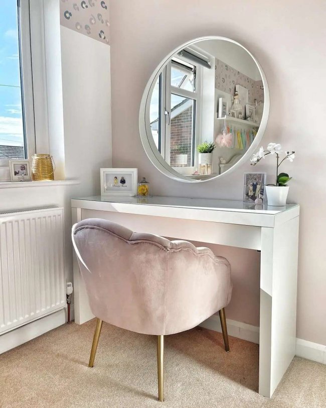 Imagem de uma mesa branca, com espelho redondo e cadeira.