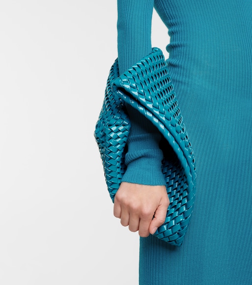 Braço de modelo usando vestido azul de manga longa e segurando bolsa da mesma cor ao redor do braço