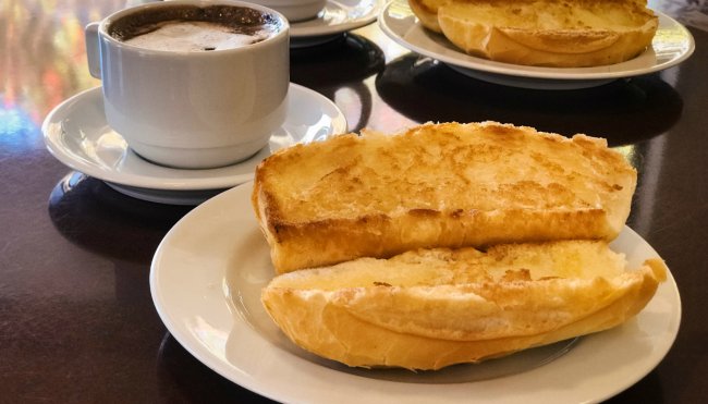 Foto de um pão na chapa ao lado de uma xícara de café