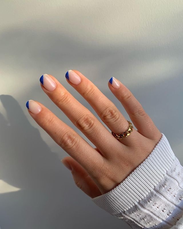 Foto de uma mão com as unhas decoradas com uma francesinha espanhola azul escura.