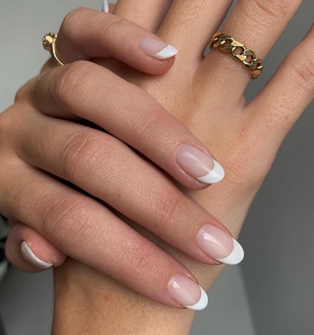 Foto de uma mão com a unha decorada com uma francesinha clássica na cor branca.