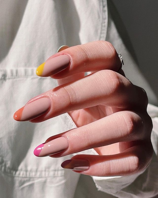 Foto das mãos de uma mulher. As unhas das mãos estão decoradas com a nail art de francesinhas espanholas coloridas.