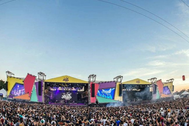 Foto mostrando uma multidão em frente ao palco principal do festival de música João Rock. Está de dia e o céu está bem azul