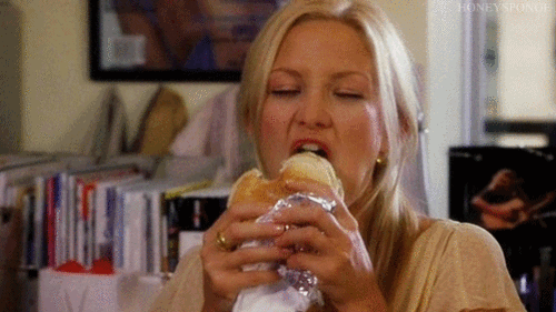Gif de uma mulher comendo um sanduíche de forma muito empolgada