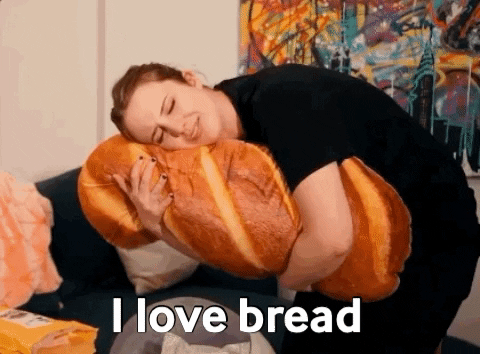 Gif de uma mulher segurando uma almofada gigante de pão e dizendo que ama muito o alimento